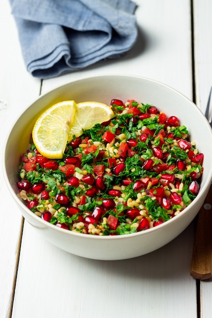 Insalata tabbouleh con bulgur, menta, prezzemolo, pomodori e melograno. Mangiare sano. Cibo vegetariano.