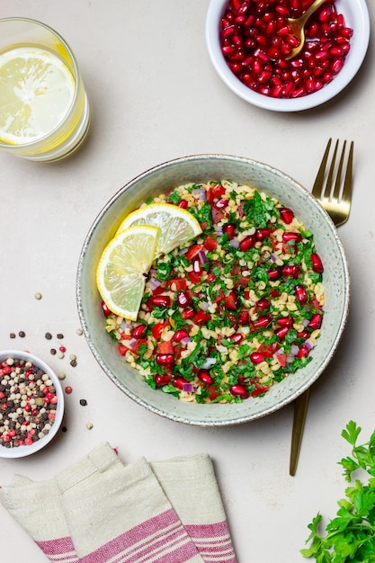 Insalata tabbouleh con bulgur, menta, prezzemolo, pomodori e melograno. Mangiare sano. Cibo vegetariano.