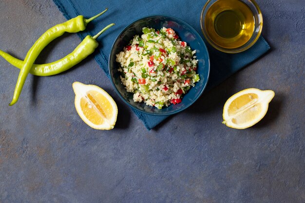 Insalata Tabbouleh con cuscus, prezzemolo, limone, pomodoro, olio d'oliva. Insalata vegetariana levantina. Cucina libanese e araba. Sfondo scuro Vista dall'alto. Spazio per il testo