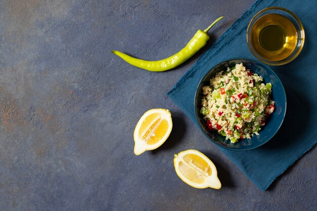 Insalata Tabbouleh con cuscus, prezzemolo, limone, pomodoro, olio d'oliva. Insalata vegetariana levantina. Cucina libanese e araba. Sfondo scuro Vista dall'alto. Spazio per il testo