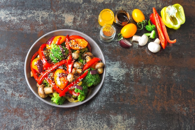 Insalata tiepida con broccoli, funghi e paprika rossa. Ciotola vegan con verdure calde su un elegante sfondo squallido. Cibo salutare. Pranzo fitness con funghi e verdure.