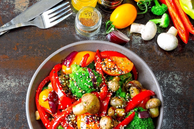 Insalata tiepida con broccoli, funghi e paprika rossa. Ciotola vegan con verdure calde su un elegante sfondo squallido. Cibo salutare. Pranzo fitness con funghi e verdure.