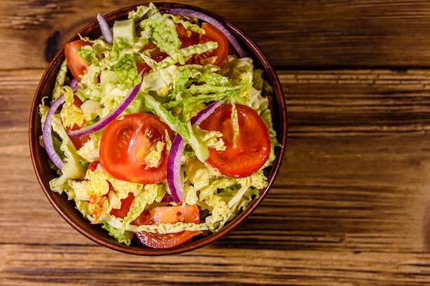 Insalata vegana con verza, pomodori e cipolla in una ciotola di ceramica. Vista dall'alto