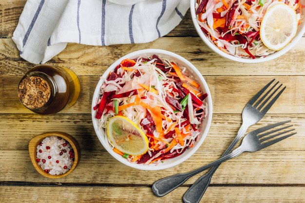 Insalata vegana sana primavera con barbabietola cruda, carota e cavolo in ciotole bianche