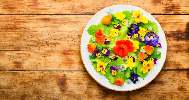 Insalata vegetariana con fiori verdi e commestibili.Insalata estiva fresca con fiori.Piatto laici con spazio copia