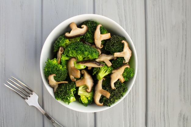 Insalata vegetariana con funghi shiitake e broccoli nella ciotola bianca su fondo di legno grigio.Vista dall'alto.spazio copia.ingredienti alimentari sani.