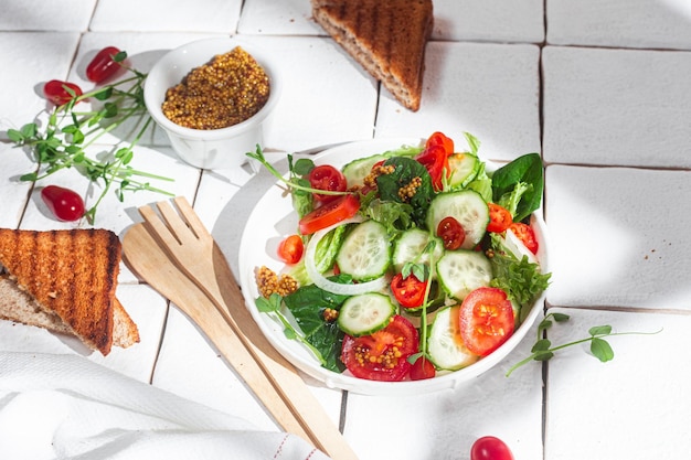 Insalata vegetariana con pomodoro cetriolo e spinaci in un piatto