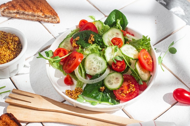 Insalata vegetariana con pomodoro cetriolo e spinaci in un piatto