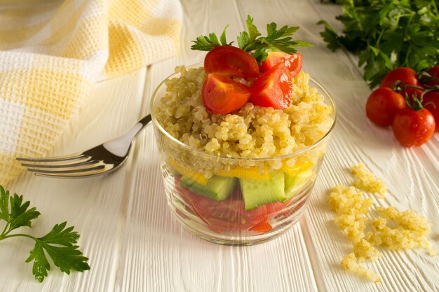 Insalata vegetariana con verdure e quinoa su fondo di legno bianco