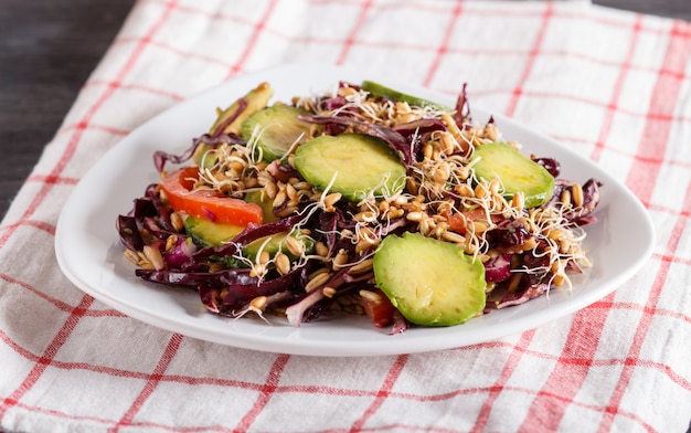 Insalata vegetariana di cavolo viola, grano germinato, pomodori e avocado sulla tovaglia di lino