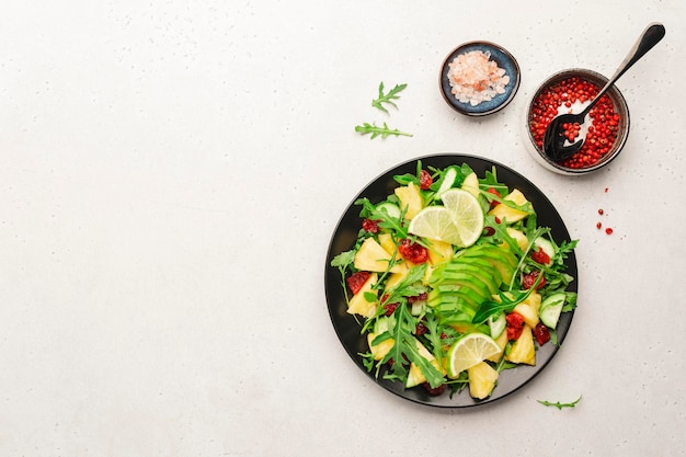 Insalata vegetariana vegana con avocado di rucola di ananas e ciliegia secca su pietra bianca vista dall'alto del tavolo da cucina Mangiare sano dieta pulita cibo concetto di perdita di peso