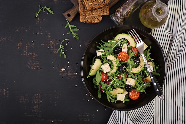 Insalata verde con avocado a fette, pomodorini, olive nere e formaggio