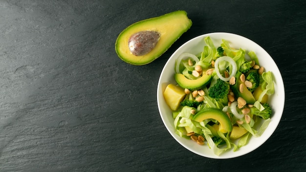 Insalata verde con avocado, cetriolo e noci sul piatto bianco