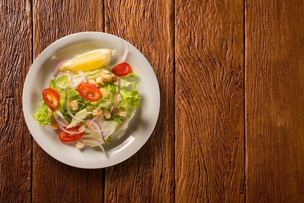 Insalata verde con limone su uno sfondo di legno