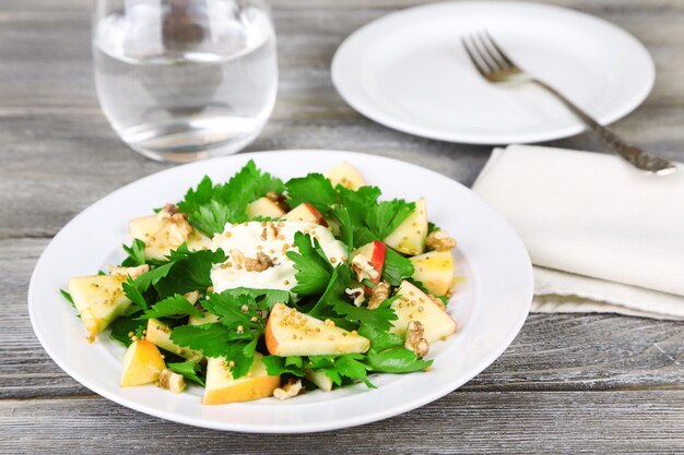 Insalata verde con mele noci e formaggio su fondo di legno