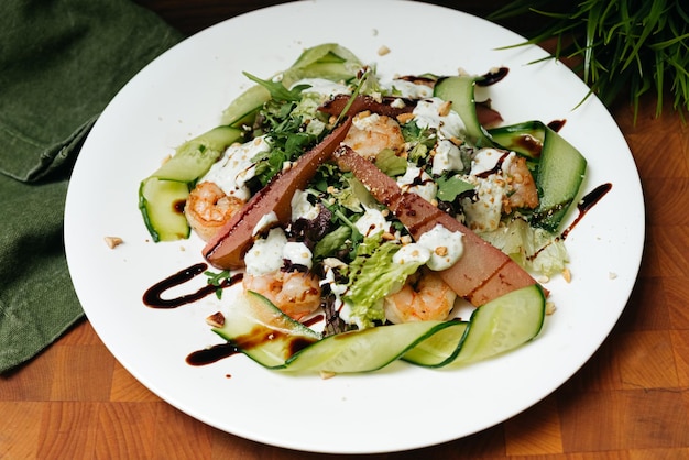 Insalata verde con pere e gamberi, noci, fette di cetriolo con salsa allo yogurt.