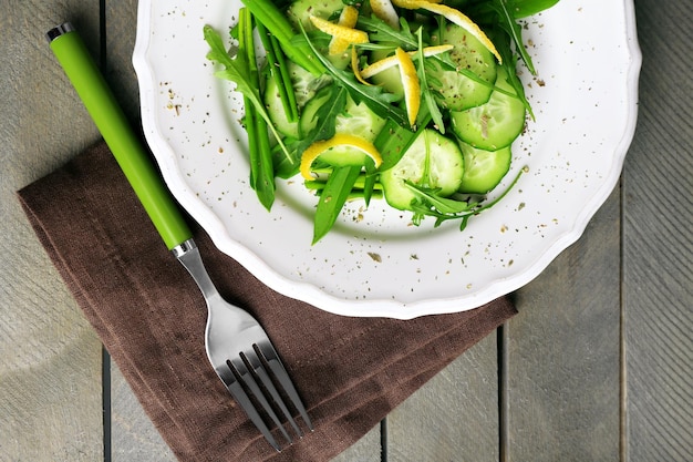 Insalata verde con rucola di cetriolo e scorza di limone sulla vista dall'alto del tavolo in legno