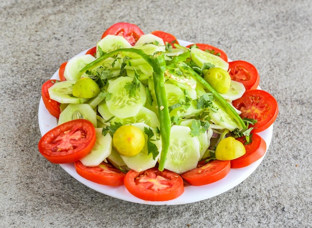 Insalata verde fresca con pomodoro cetriolo limone servito in piatto isolato su sfondo grigio vista dall'alto del cibo pakistano e delle spezie indiane