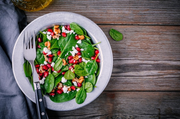 Insalata verde fresca con spinaci noci formaggio di capra e melograno su fondo di legno