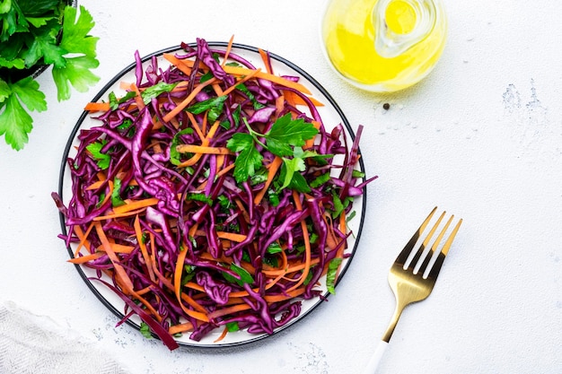 Insalata vitaminica autunnale con cavolo rosso carota prezzemolo e olio d'oliva condimento su sfondo bianco tavolo da cucina vista dall'alto