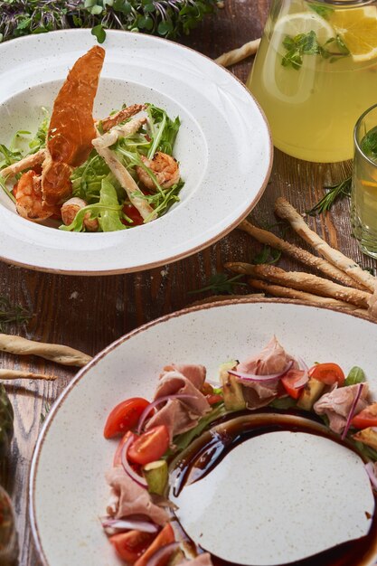 Insalate con maiale bollito e gamberi su un tavolo di legno con salse