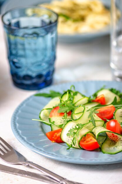 Insalate di pomodori, cetrioli e rucola su un piatto blu si aprono improvvisamente