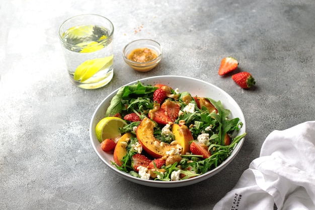 Insalatiera con rucola, fragole, ricotta, nettarina e pasta di arachidi. concetto di alimentazione sana