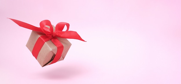 Insegna con il nastro rosso del contenitore di regalo sul rosa.