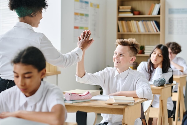 Insegnante afroamericano che dà il cinque allo studente per la sua risposta giusta durante la lezione