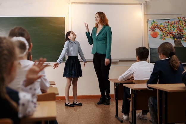 Insegnante anziano sorridente vicino alla lavagna che chiede allo studente alla lezione di matematica