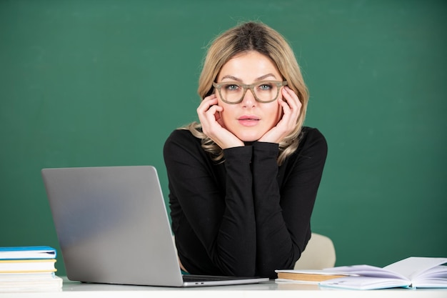 Insegnante attraente concentrato Ritratto di giovane donna intelligente con gli occhiali con libro sulla lavagna in classe al liceo o collage Studentessa studio all'università