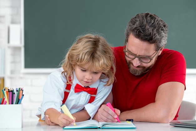 Insegnante che aiuta l'allievo dell'allievo della scuola elementare nell'insegnante della classe e nell'apprendimento del bambino a