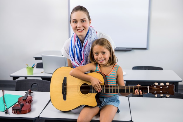 Insegnante che aiuta la ragazza a suonare la chitarra