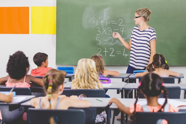 Insegnante che insegna matematica ai bambini della scuola in aula