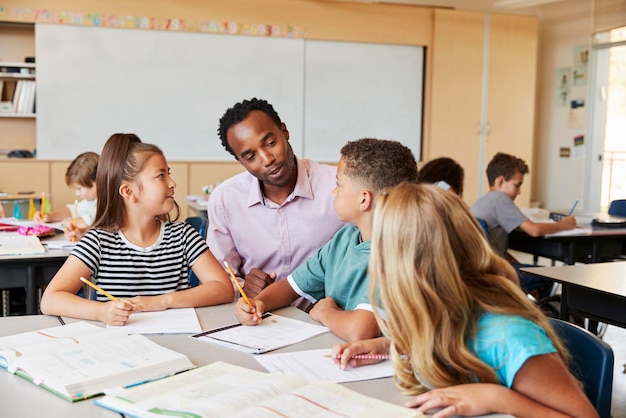 Insegnante che lavora con i bambini delle scuole elementari alla loro scrivania