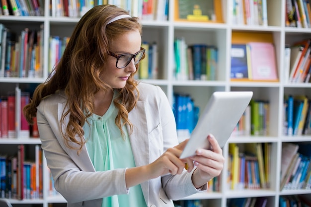 Insegnante che utilizza la compressa di digital nella biblioteca