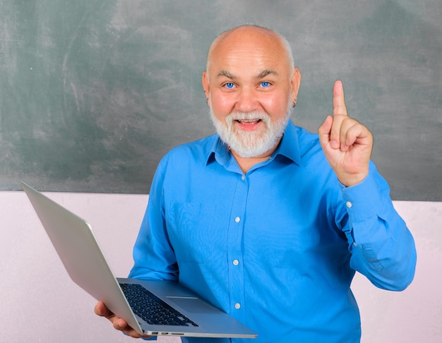 Insegnante con laptop in classe che punta con il dito in alto Professore che dà lezione agli studenti