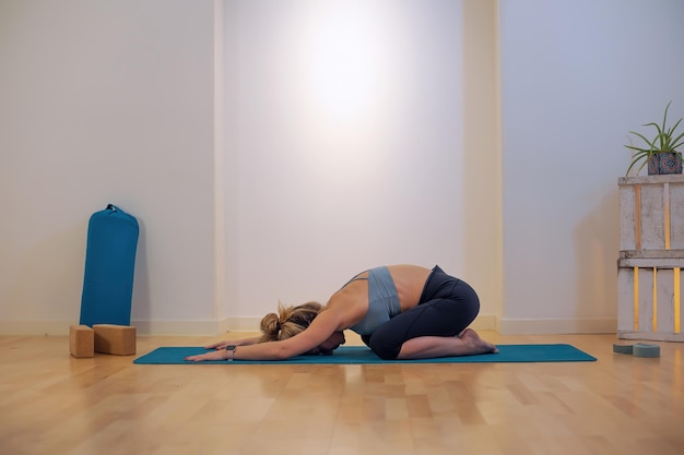 Insegnante di yoga che mostra la donna di posizione di balasana sul tappetino alla scuola di yoga