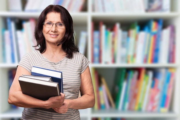 Insegnante donna matura con libri sullo sfondo