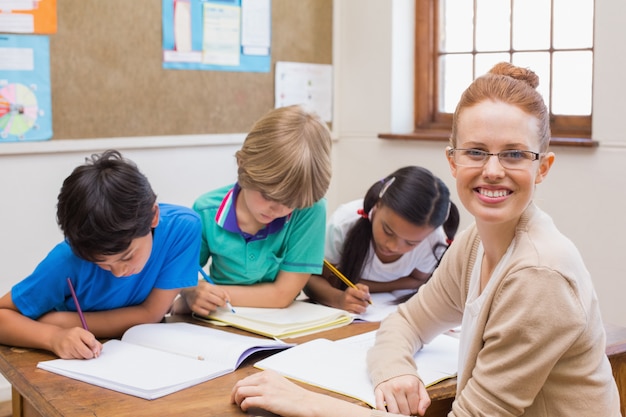 Insegnante e alunni lavorano insieme alla scrivania alla scuola elementare