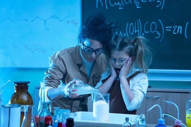 Insegnante e bambina durante la lezione di chimica mescolando prodotti chimici