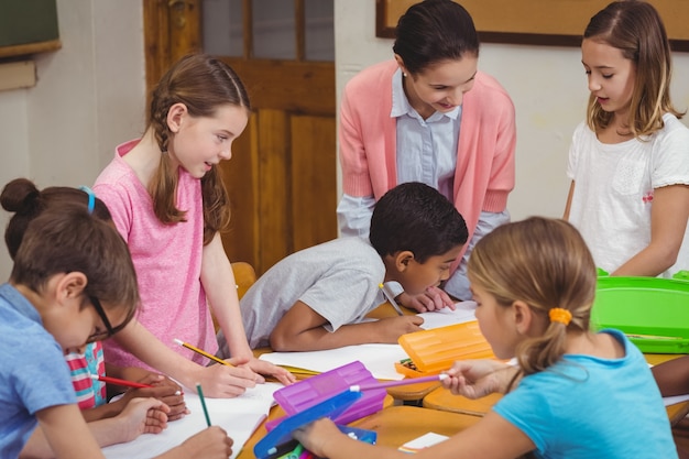 Insegnante ed allievi che lavorano insieme allo scrittorio