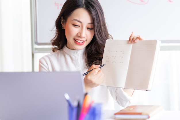 Insegnante femminile asiatica che insegna in linea a casa