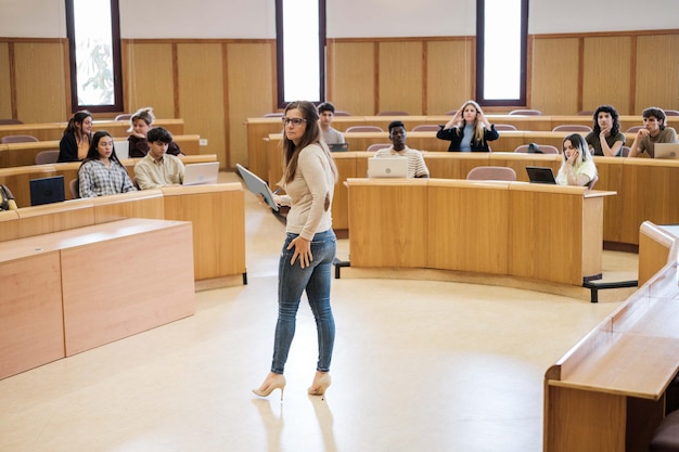 Insegnante femminile che dà classe agli studenti dell'università in un'aula circolare