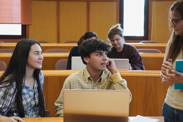 Insegnante femminile matura che lavora con i giovani studenti all'interno dell'aula universitaria