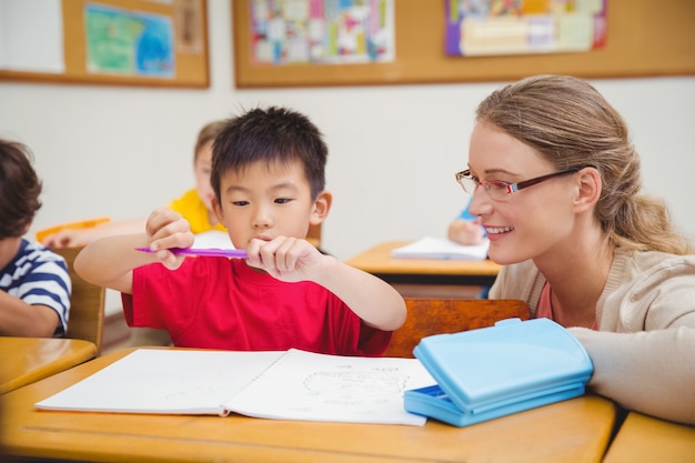 Insegnante grazioso che aiuta allievo in aula