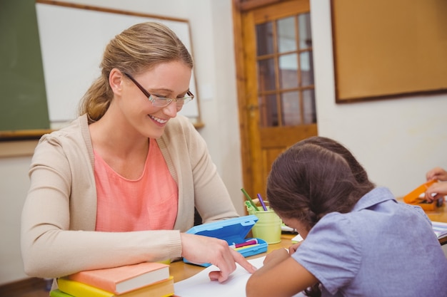 Insegnante grazioso che aiuta allievo in aula