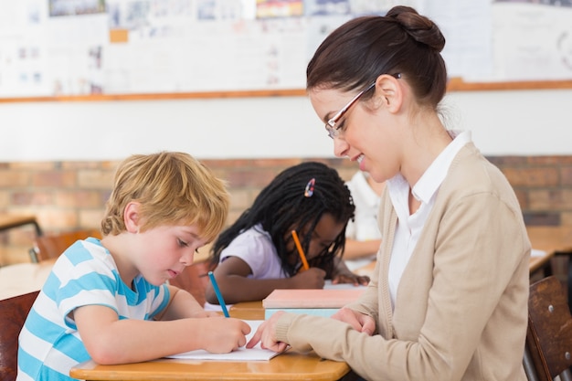 Insegnante grazioso che aiuta allievo in aula