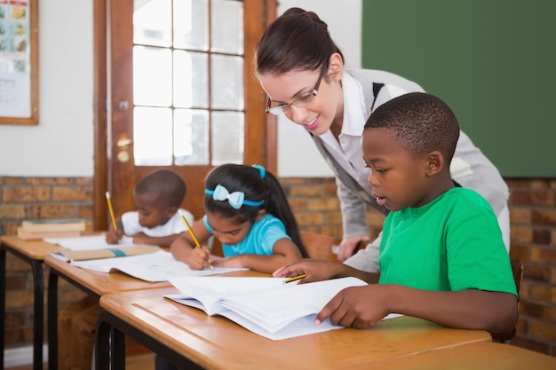 Insegnante grazioso che aiuta allievo in aula