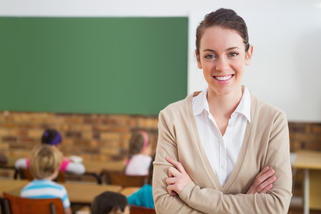 Insegnante grazioso che sorride alla macchina fotografica alla parte posteriore dell&#39;aula